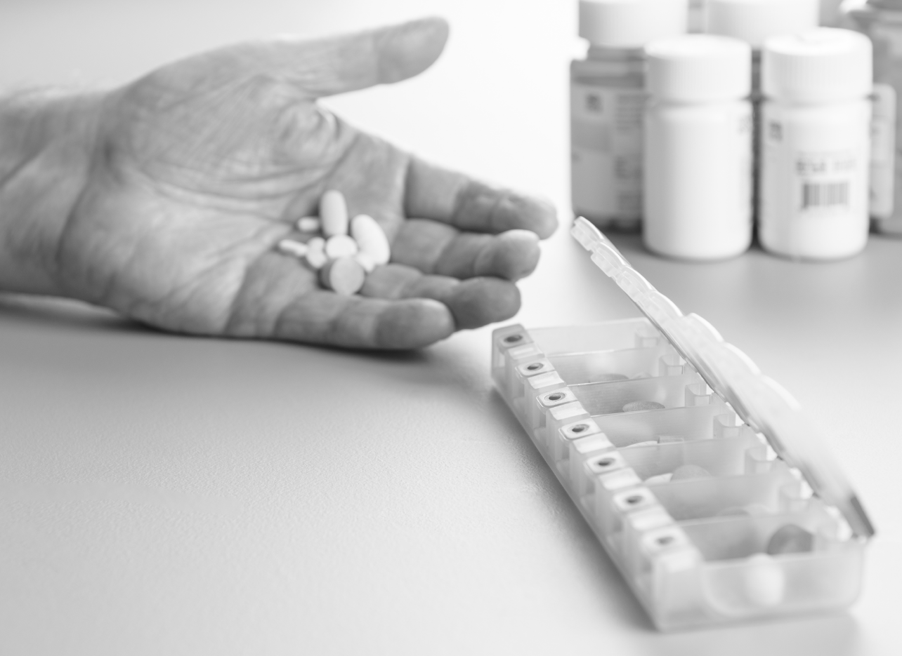 a person's hand with medication and a medication sorter